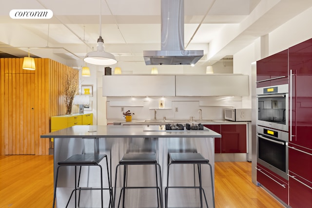 kitchen featuring red cabinetry, white microwave, visible vents, and island range hood