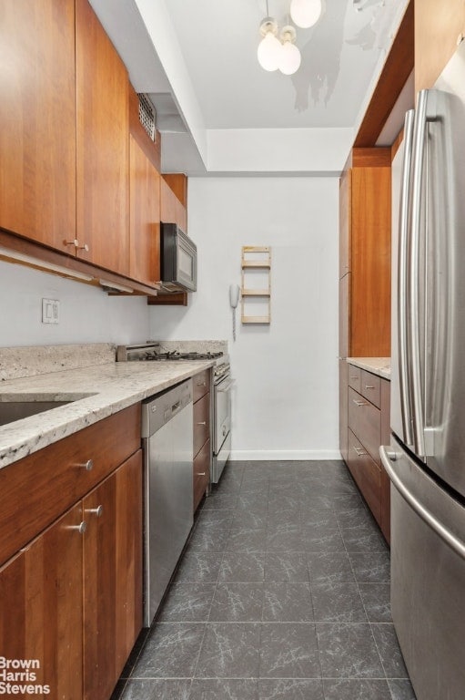 kitchen with stainless steel appliances, a chandelier, and light stone counters