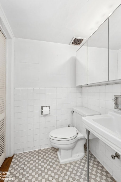 bathroom with tile walls and toilet