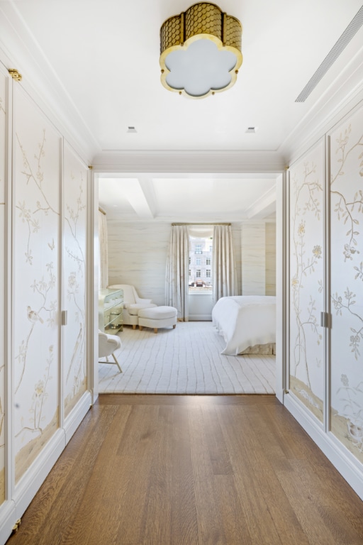 unfurnished bedroom with wallpapered walls, ornamental molding, and wood finished floors