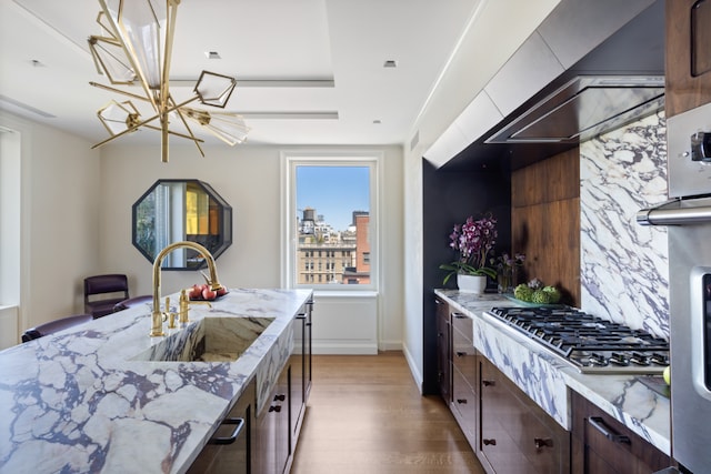 kitchen featuring a city view, stainless steel gas cooktop, wood finished floors, a sink, and light stone countertops