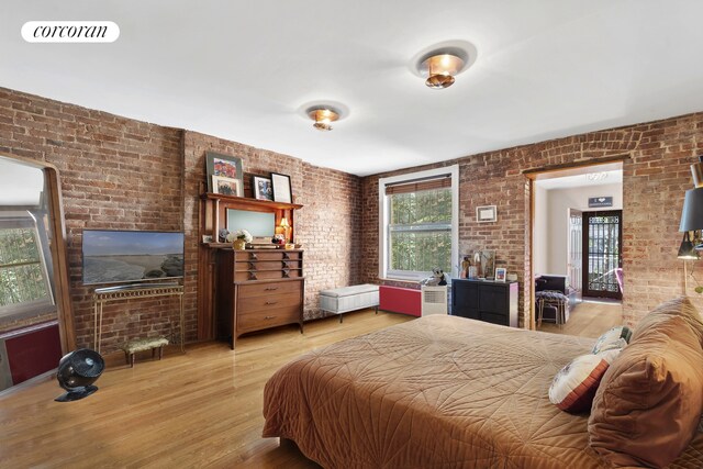 bedroom with visible vents, wood finished floors, and brick wall