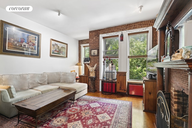 living area featuring visible vents, light wood finished floors, and brick wall