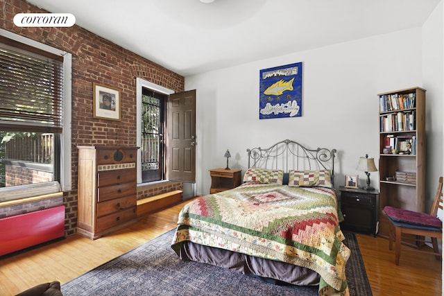 bedroom featuring wood finished floors and brick wall