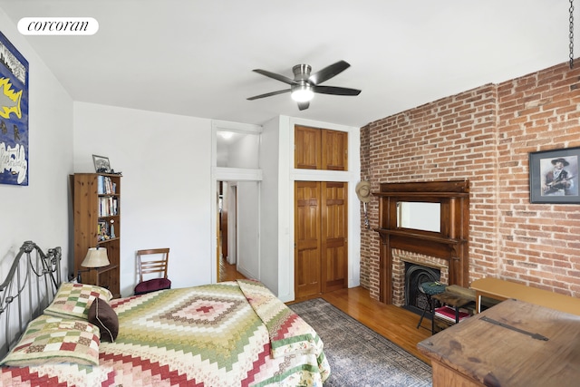 bedroom featuring a fireplace, wood finished floors, brick wall, and visible vents
