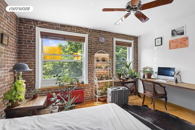 bedroom featuring wood finished floors, brick wall, a ceiling fan, and visible vents