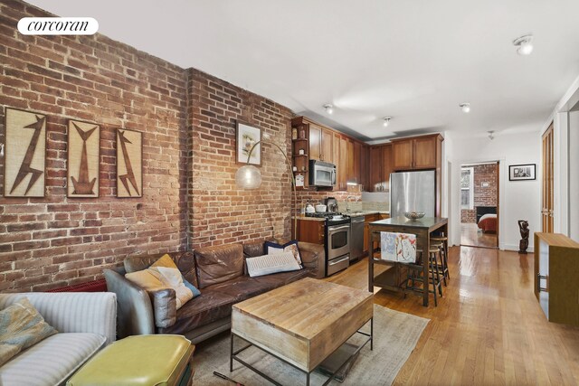 living room featuring baseboards, light wood-type flooring, and brick wall