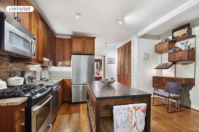 kitchen featuring a center island, light wood finished floors, a sink, and stainless steel appliances