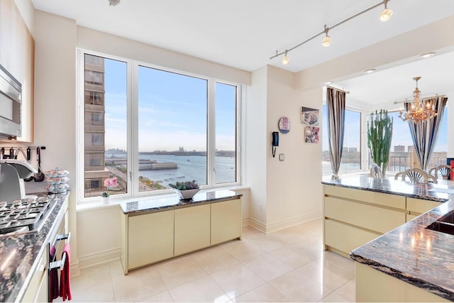 kitchen featuring an inviting chandelier, light tile patterned floors, cream cabinetry, and a water view