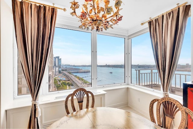 dining space with a water view, crown molding, and a notable chandelier