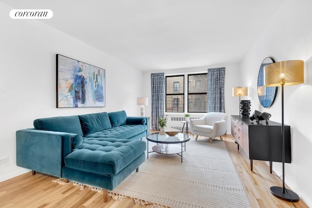 living area with radiator heating unit, visible vents, light wood finished floors, and baseboards