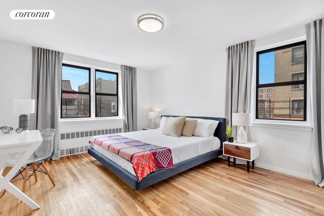 bedroom featuring radiator and hardwood / wood-style flooring