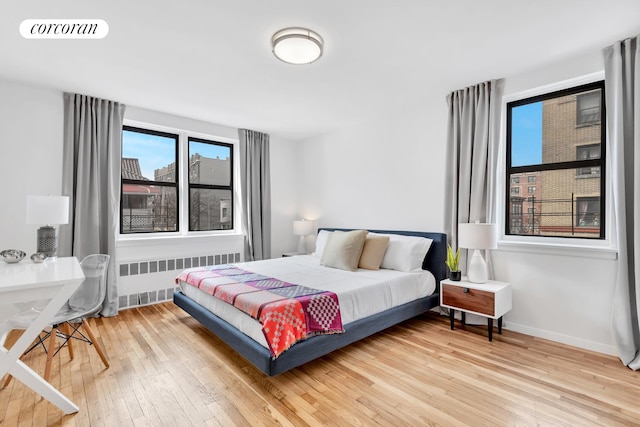 bedroom featuring radiator, wood finished floors, visible vents, and multiple windows