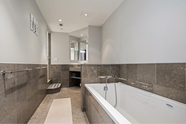 full bathroom featuring vanity, visible vents, tiled bath, tile walls, and tile patterned floors