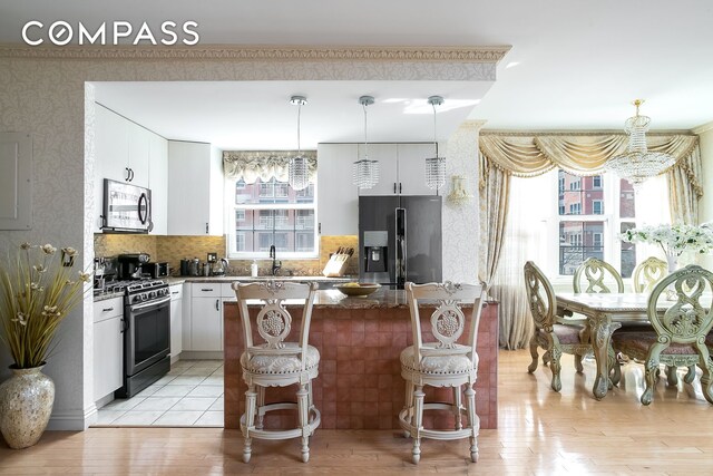 kitchen featuring pendant lighting, white cabinetry, a breakfast bar area, dark stone counters, and stainless steel appliances