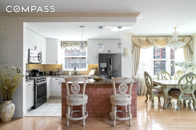 kitchen featuring a sink, appliances with stainless steel finishes, a breakfast bar area, an inviting chandelier, and wallpapered walls