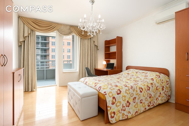 bedroom with a chandelier, light wood-style flooring, crown molding, an AC wall unit, and access to outside