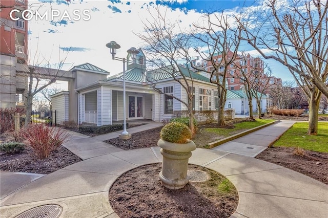 view of front of home featuring a standing seam roof, metal roof, fence, and french doors
