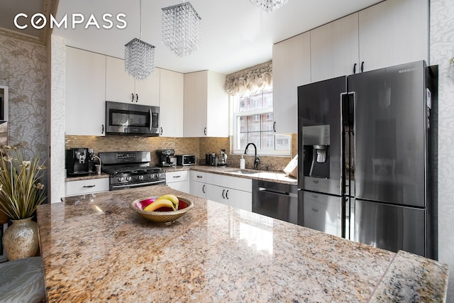 135 Oceana Dr E Unit 2C, New York City, NY 11235 - kitchen with stainless steel appliances, a sink, decorative backsplash, light stone countertops, and hanging light fixtures