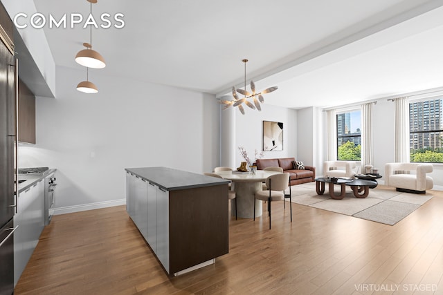 kitchen featuring decorative light fixtures, dark countertops, modern cabinets, a kitchen island, and wood finished floors