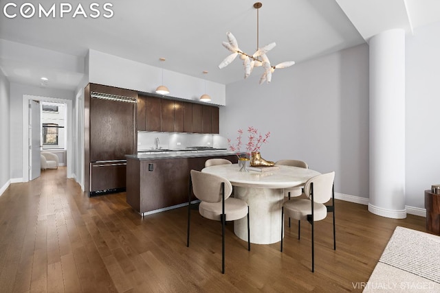 kitchen with dark brown cabinetry, sink, a center island, dark hardwood / wood-style flooring, and a notable chandelier