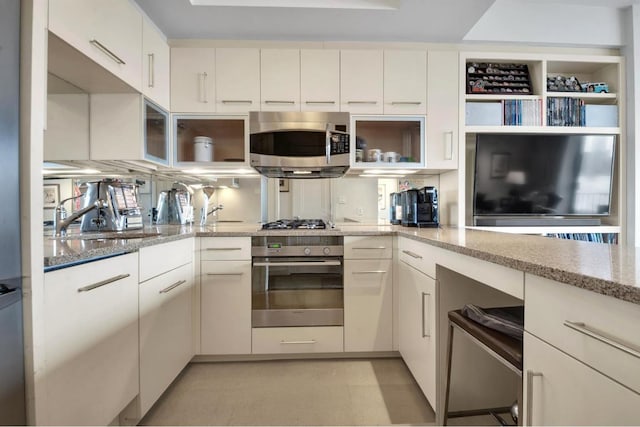 kitchen featuring light stone counters, sink, stainless steel appliances, and white cabinets