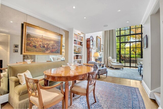 dining room with floor to ceiling windows, light hardwood / wood-style floors, and built in features