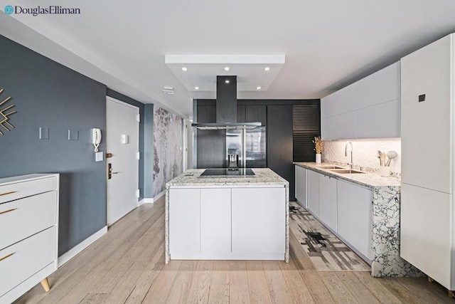 kitchen with white cabinets, a center island, sink, island range hood, and light wood-type flooring