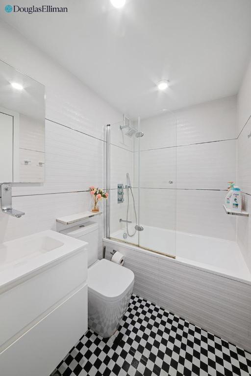 full bathroom featuring combined bath / shower with glass door, vanity, and toilet