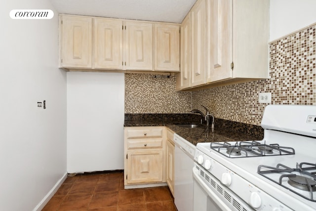 kitchen with white appliances, dark tile patterned flooring, sink, and decorative backsplash