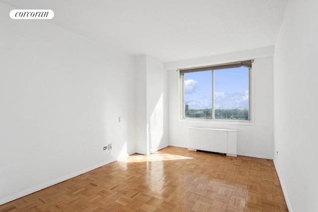 unfurnished room with radiator heating unit and light parquet floors