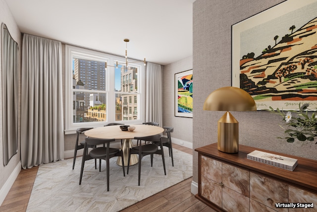 dining space with a chandelier, a view of city, light wood-style flooring, and baseboards