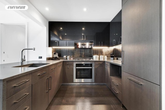 kitchen featuring extractor fan, appliances with stainless steel finishes, backsplash, dark wood-type flooring, and sink