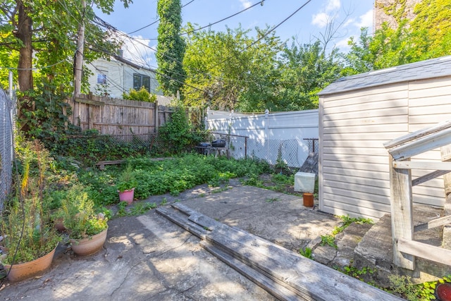 view of yard featuring an outbuilding, a shed, a patio area, and fence private yard