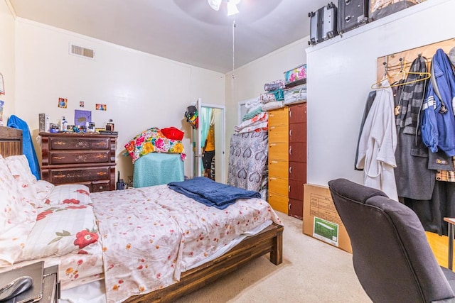 bedroom with ornamental molding, visible vents, ceiling fan, and carpet flooring