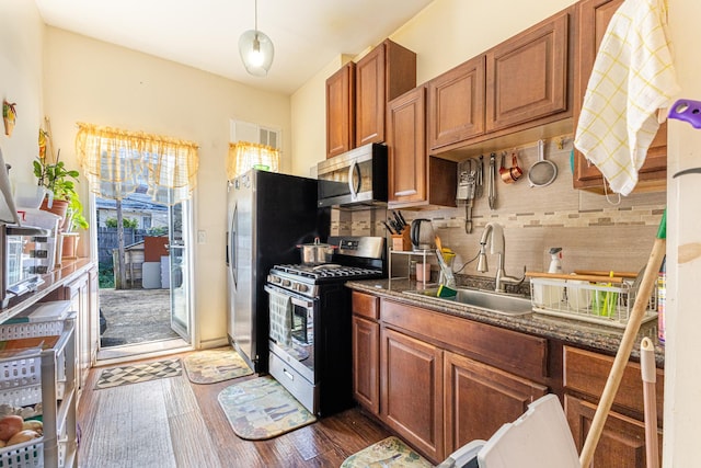 kitchen featuring stainless steel appliances, backsplash, a sink, and brown cabinets