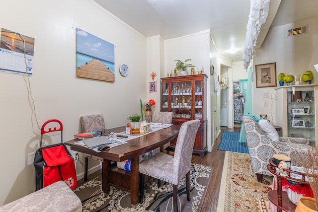 dining room with visible vents, crown molding, and wood finished floors