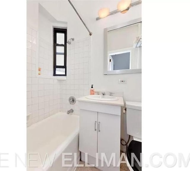 full bathroom with tiled shower / bath, vanity, and toilet