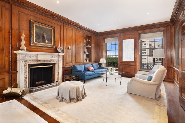 living area featuring crown molding, wood walls, a fireplace, and built in shelves