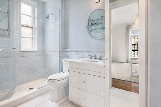 full bath featuring toilet, a stall shower, tile walls, and wainscoting