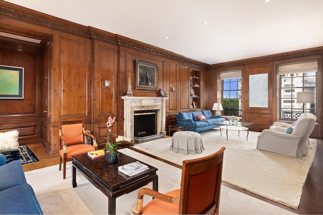 living area featuring crown molding, wood walls, a decorative wall, and a premium fireplace