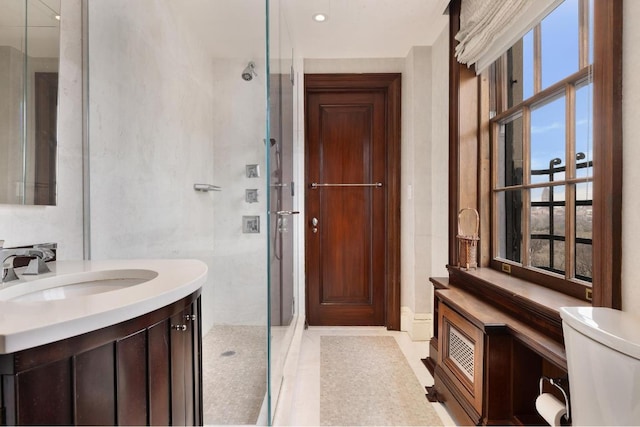 bathroom with walk in shower, vanity, and toilet