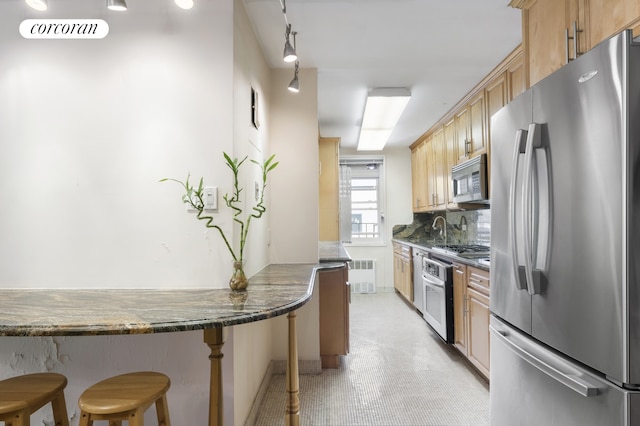 kitchen with radiator, light floors, stainless steel appliances, a kitchen bar, and backsplash