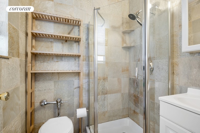 bathroom featuring a shower with door, vanity, and toilet