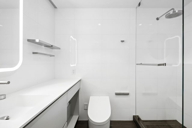 bathroom with vanity, tile walls, toilet, and a tile shower