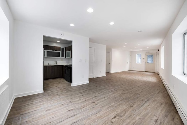 unfurnished living room with baseboard heating and light wood-type flooring