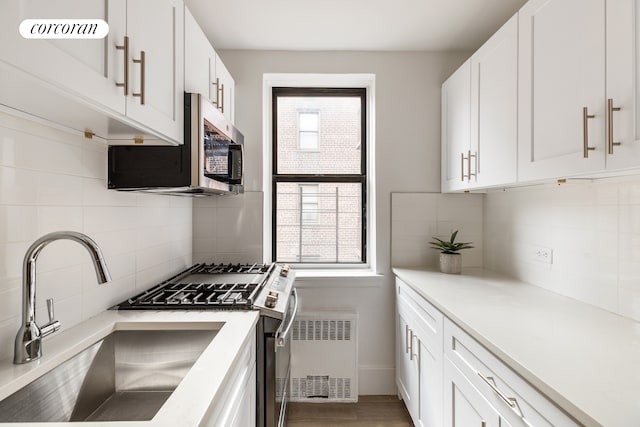 2420 Morris Ave Unit 2K, New York City, NY 10468 - kitchen featuring appliances with stainless steel finishes, backsplash, a sink, white cabinetry, and light countertops