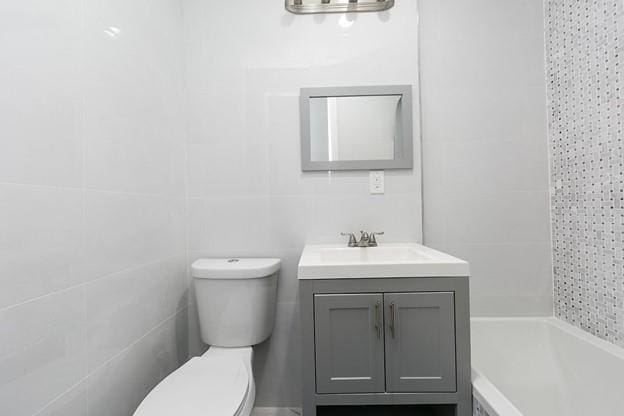 full bath with vanity, toilet, and tile walls