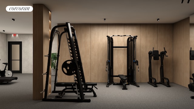 exercise room featuring light carpet and wood walls