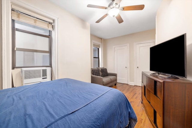 bedroom featuring light wood-style floors, a ceiling fan, and cooling unit